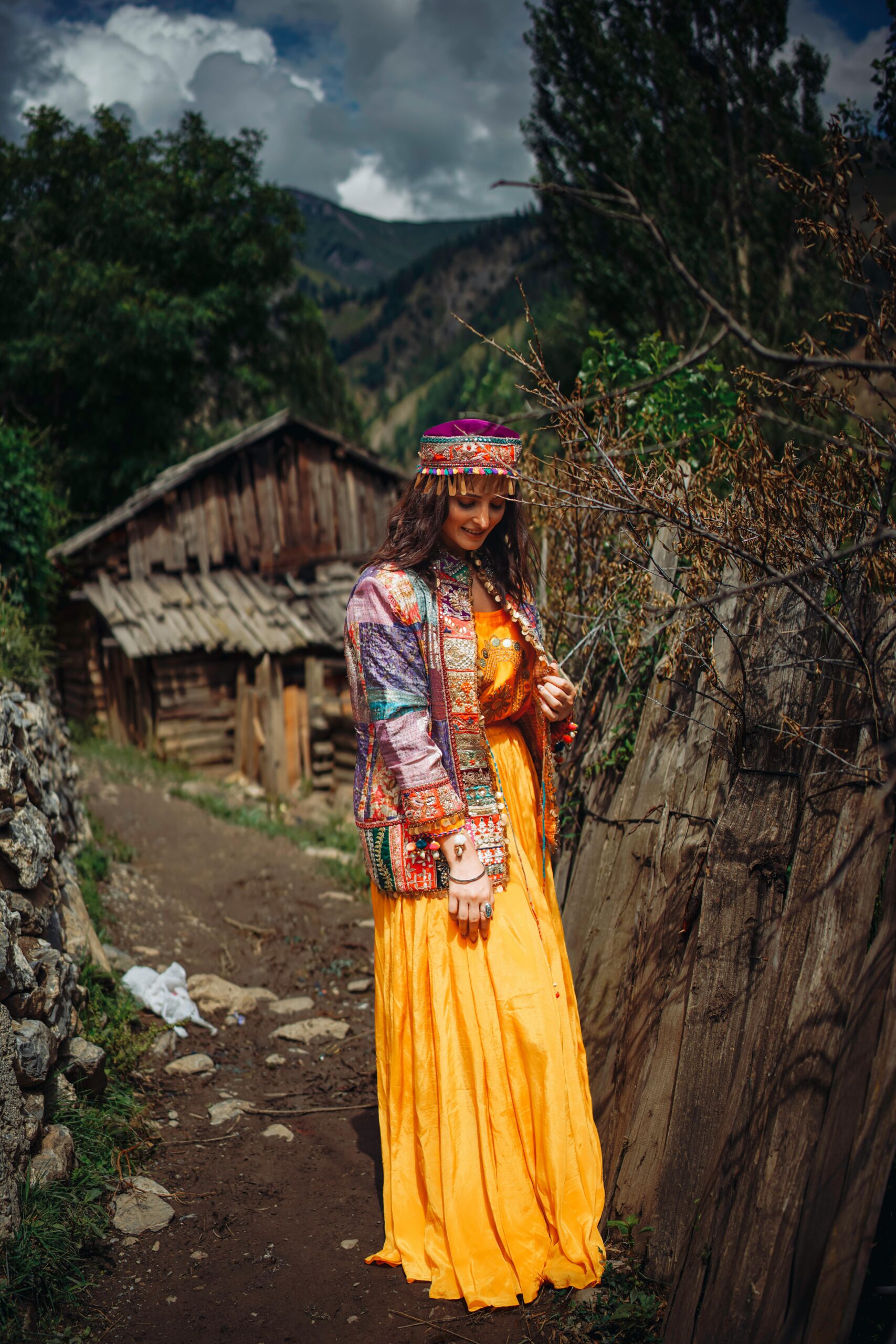 A woman in a vibrant yellow dress explores the beautiful Gurez countryside, showcasing traditional fashion.